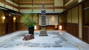 A traditional Japanese courtyard with a stone lantern, a potted tree, and a rock. - Atami Sekitei (Atami)