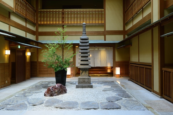 Ein traditioneller japanischer Innenhof mit einem Steinglaternen, einer Topfpflanze und einem Stein.