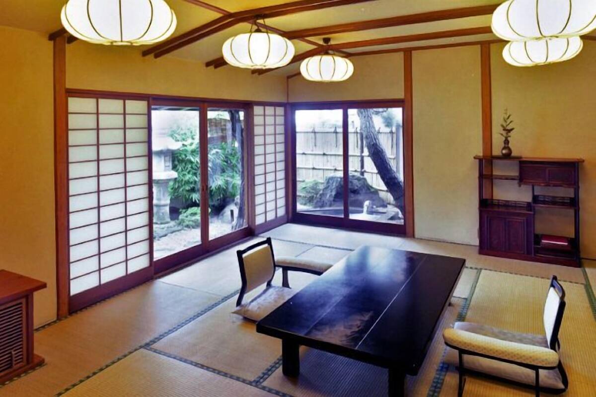Um quarto japonês tradicional com tatames, uma mesa baixa e portas deslizantes.