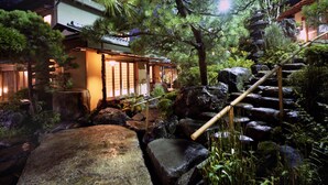 A traditional Japanese garden with a wooden staircase leading up to a building with sliding doors. - Atami Sekitei (Atami)