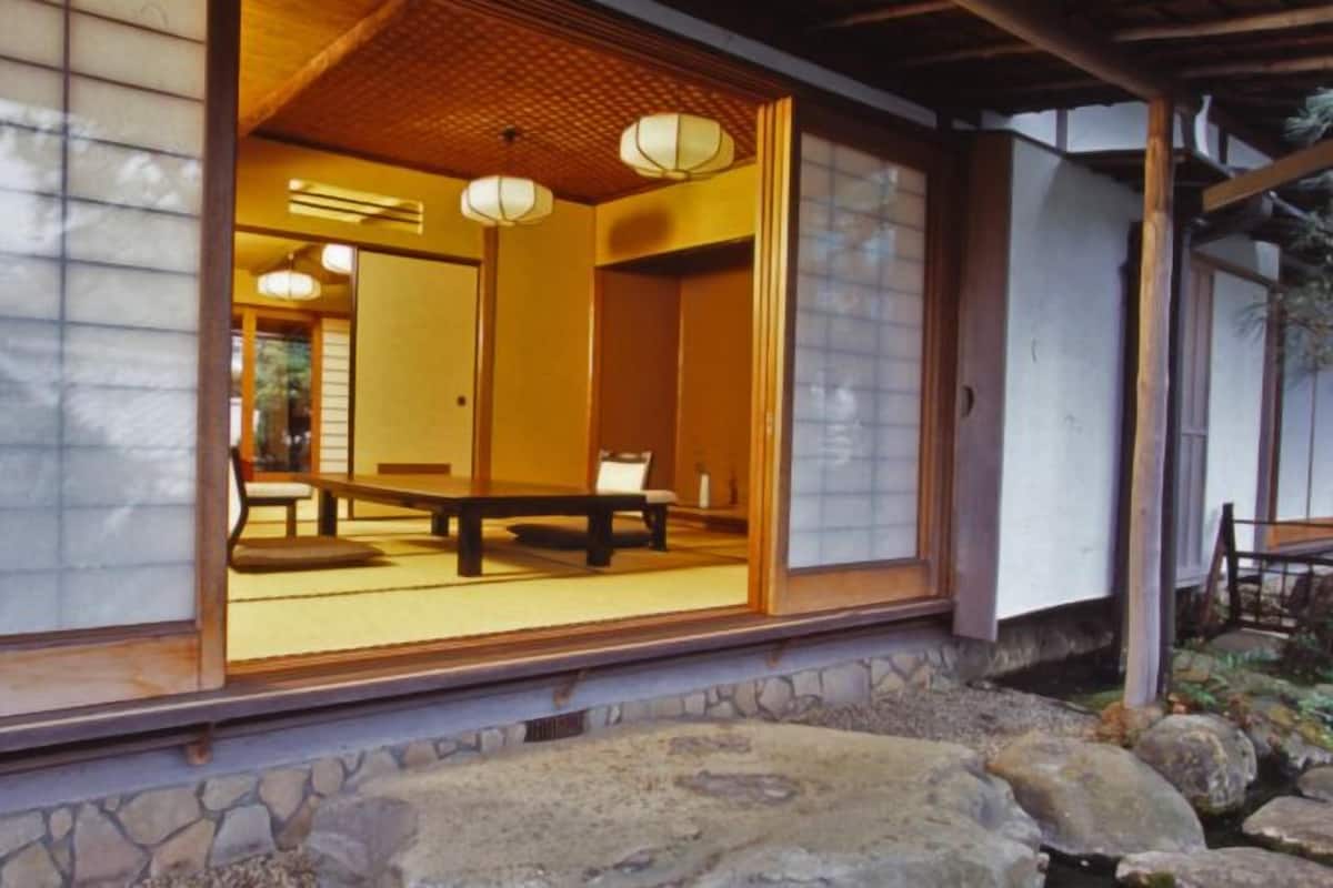 Um quarto japonês tradicional com tatames, uma mesa de madeira baixa e portas deslizantes.