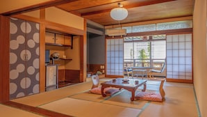 A traditional Japanese room with tatami flooring, a low table with cushions, sliding doors, and a ceiling fan. - Yudanaka Onsen Andaikan (Yamanouchi)