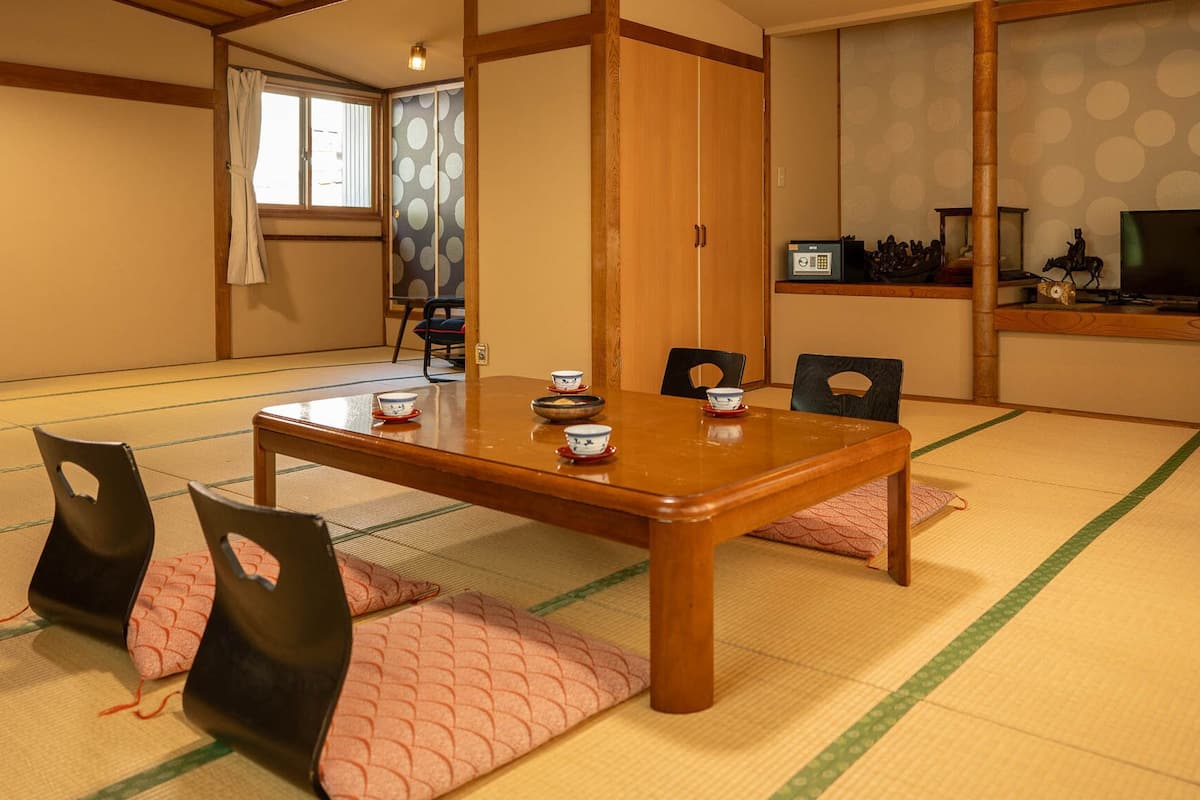 Une pièce de style japonais traditionnel, avec un sol recouvert de tatamis, une petite table en bois et un téléviseur.