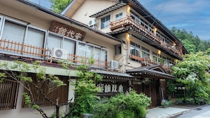 A traditional Japanese building with multiple windows, a wooden balcony, and signage indicating it is a ryokan. - Yudanaka Onsen Andaikan (Yamanouchi)
