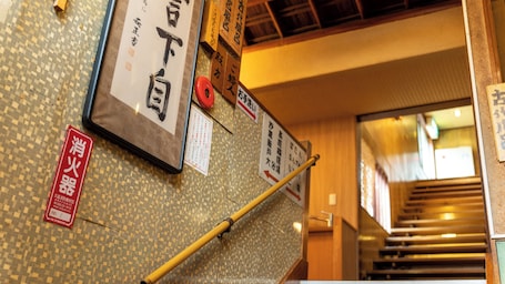 A staircase with signage in Japanese, a fire extinguisher, and a bamboo handrail.