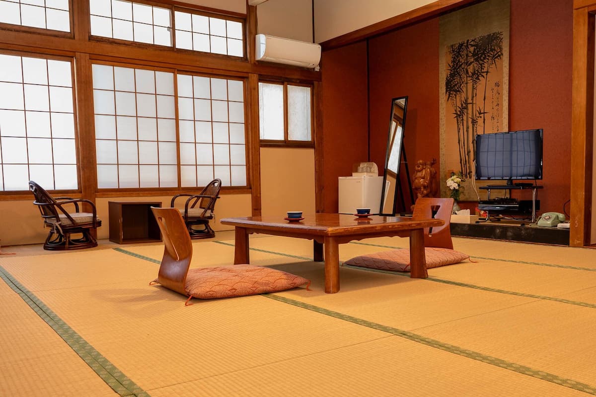 Une pièce de style japonais traditionnel, avec un sol recouvert de tatamis, une table basse et des chaises.