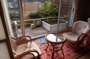 A balcony with wicker furniture, a small stool, and a wooden table. - Gero Onsen Bosenkan (Gero)