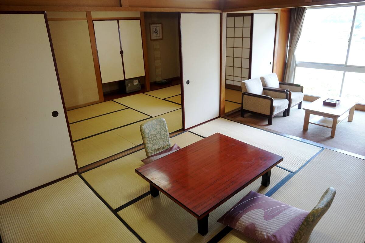 Una habitación japonesa tradicional con suelo de tatami, una mesa de madera, un sofá y una puerta corredera.