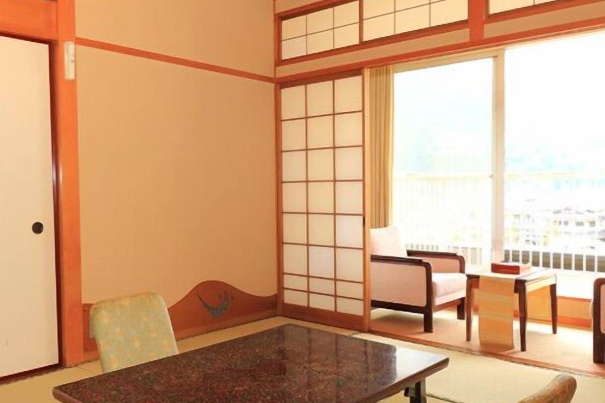 Ein traditioneller japanischer Raum mit Tatami-Bodenbelag, einem niedrigen Tisch und einer Schiebetür.