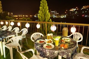 An outdoor dining area with tables and chairs, surrounded by lanterns, with a cityscape view in the background. - Gero Onsen Bosenkan (Gero)