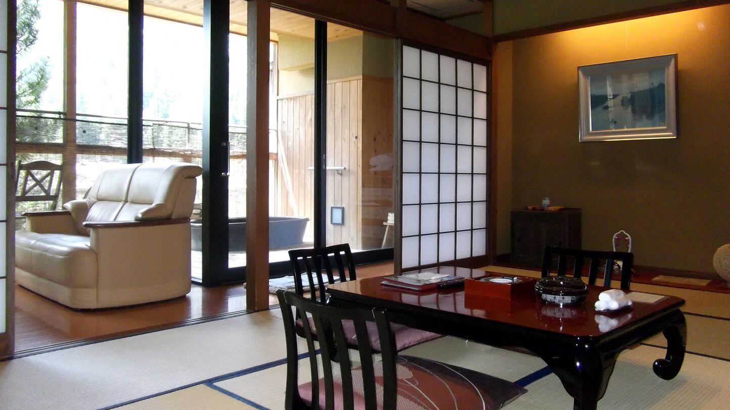 Een traditionele Japanse kamer met tatami vloerbedekking, een lage houten tafel en een bank.