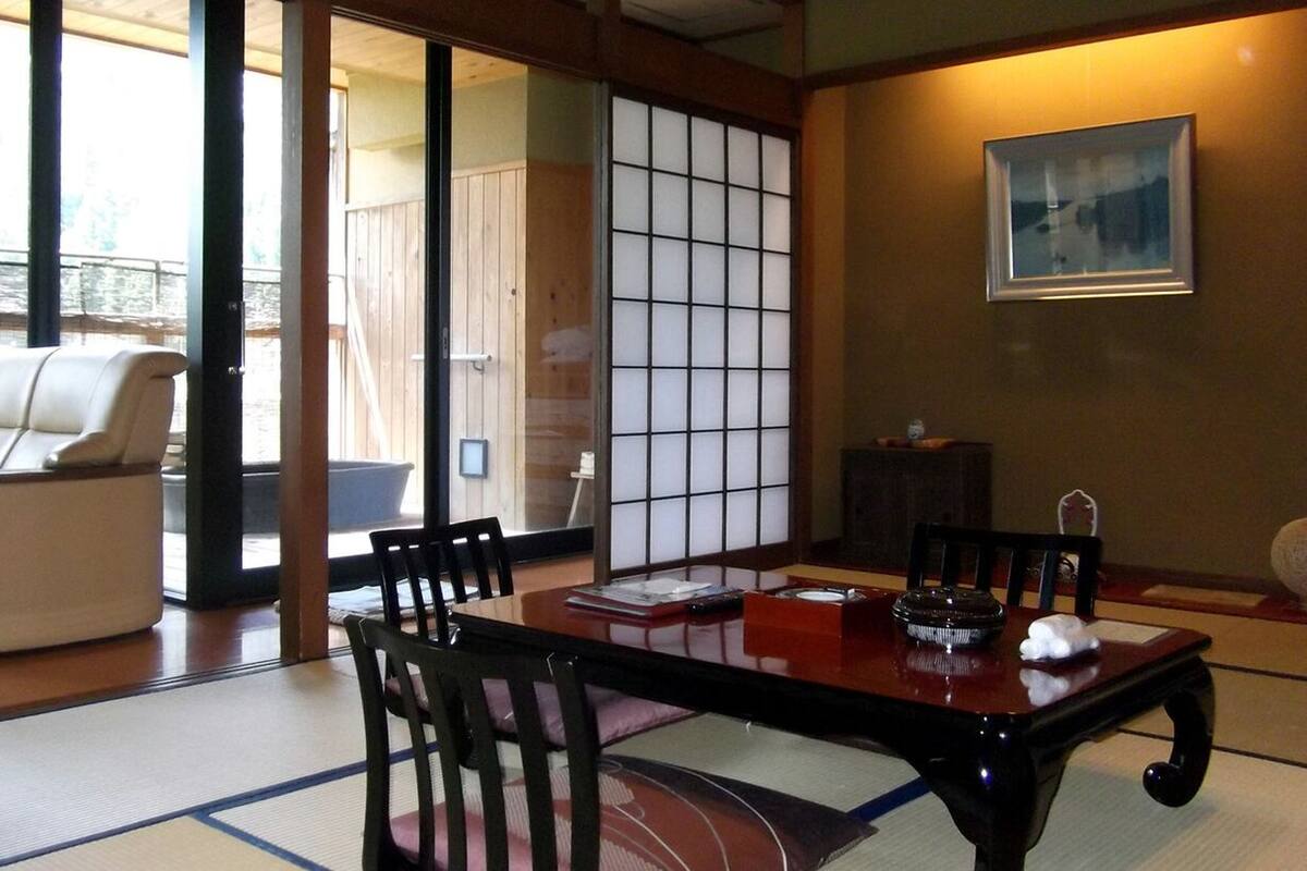 Ein traditioneller japanischer Raum mit Tatami-Boden, einem niedrigen Holztisch und einer Couch.
