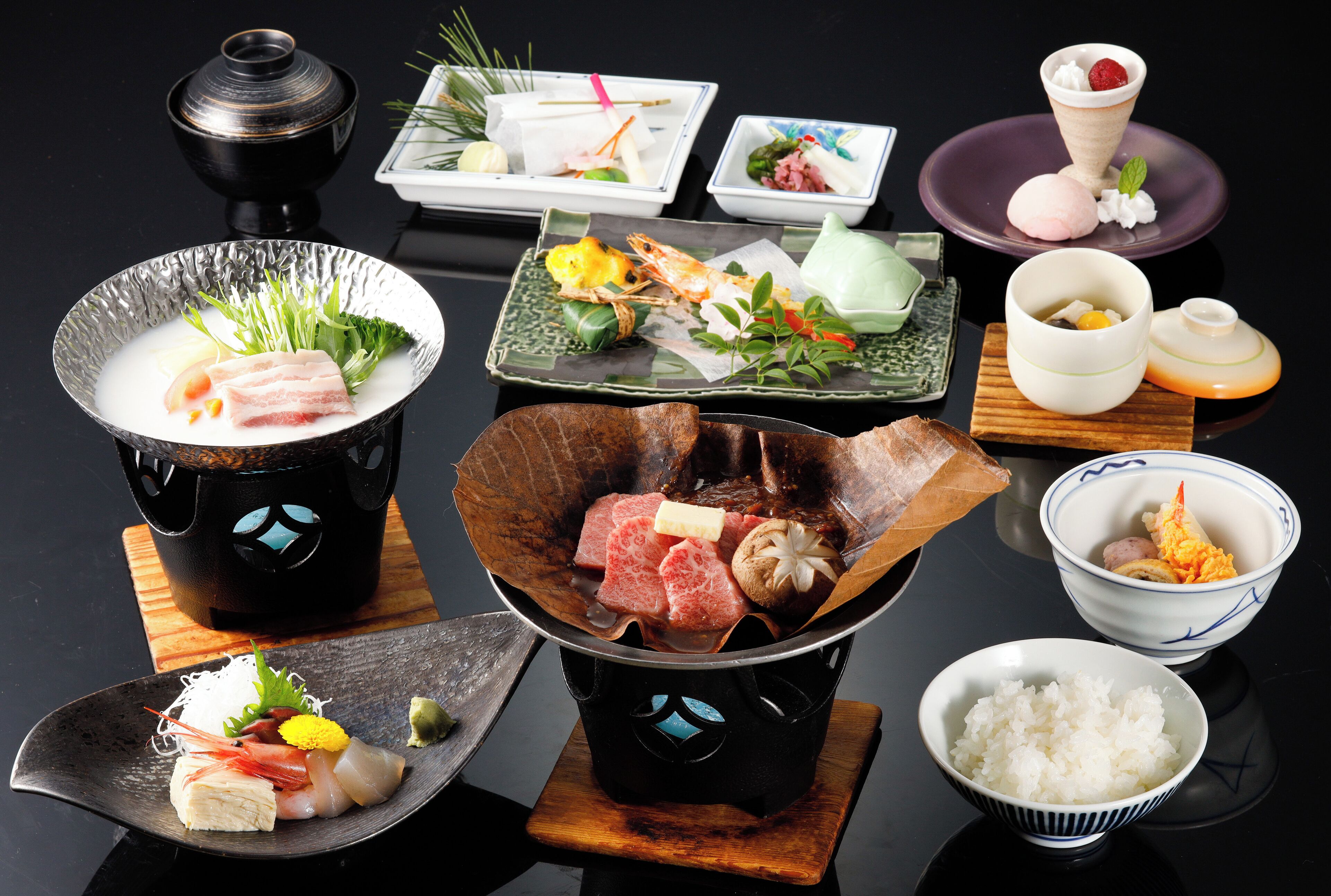 Une variété de plats japonais, notamment des sushis, des sashimis et des bols de riz, présentés sur une table noire.