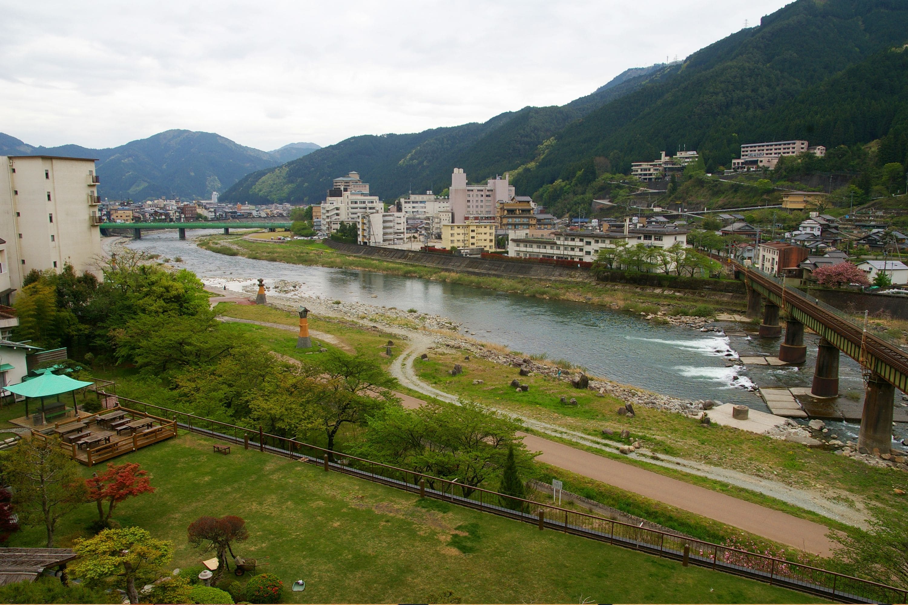 A riverside town with a bridge, buildings, and a park.