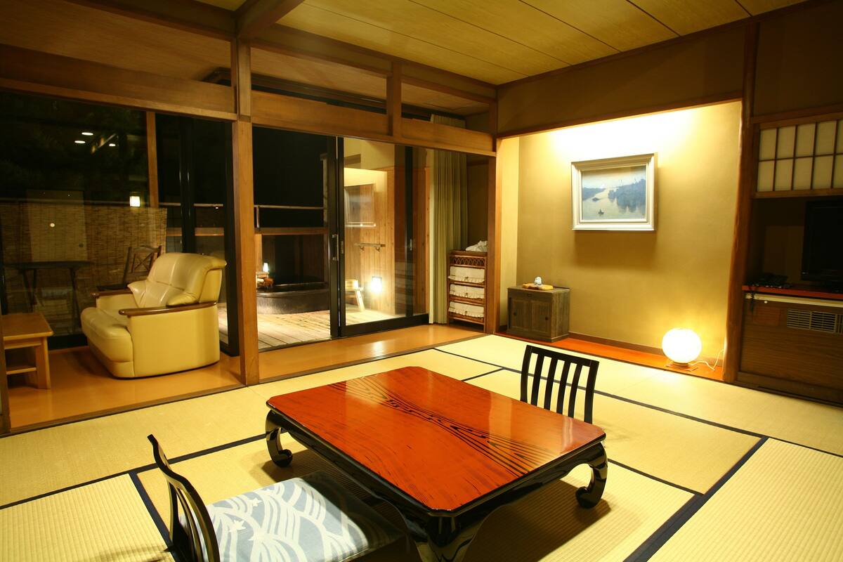 Una habitación japonesa tradicional con suelo de tatami, una mesa de madera baja y un sofá.