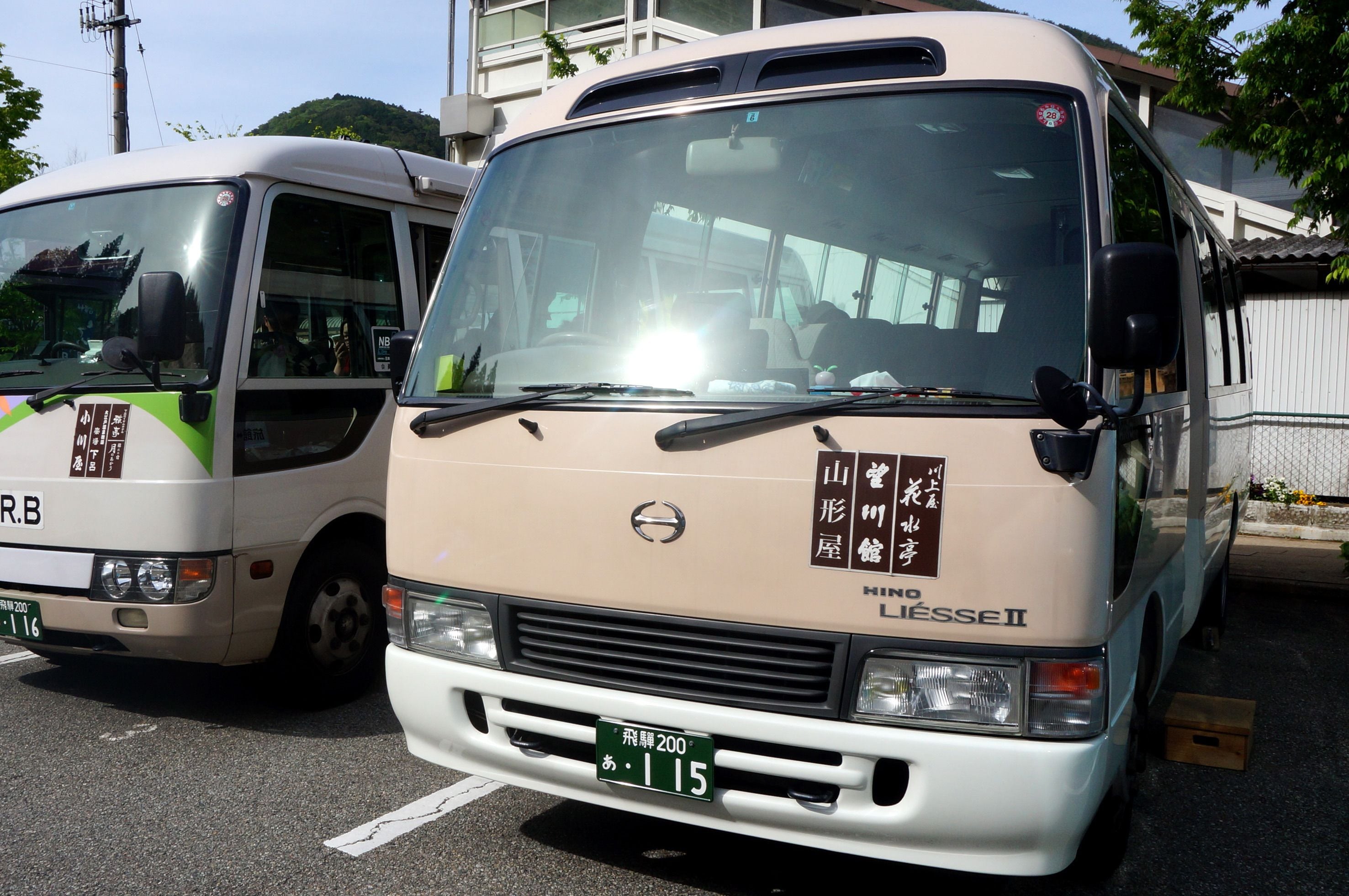 Een beige Hino L'ESSIE bus met een zichtbaar kenteken en een sticker aan de zijkant.