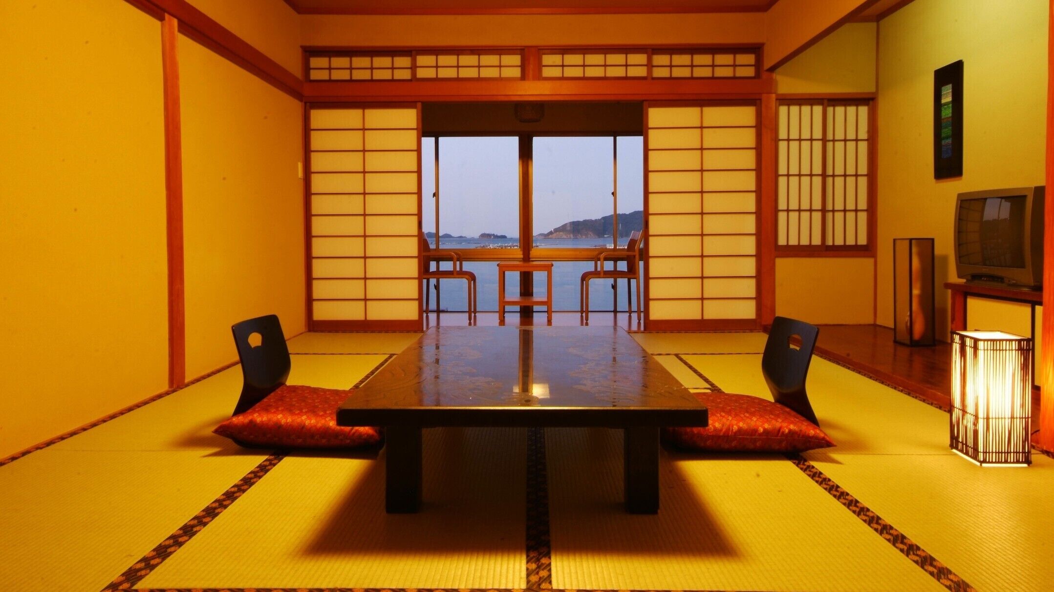 A traditional Japanese room with tatami flooring, a low table, and sliding doors.