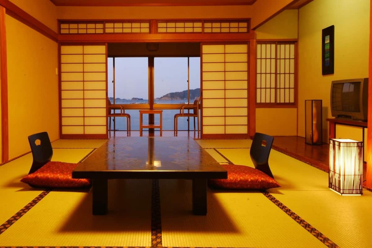 A traditional Japanese room with tatami flooring, a low table, and sliding doors.
