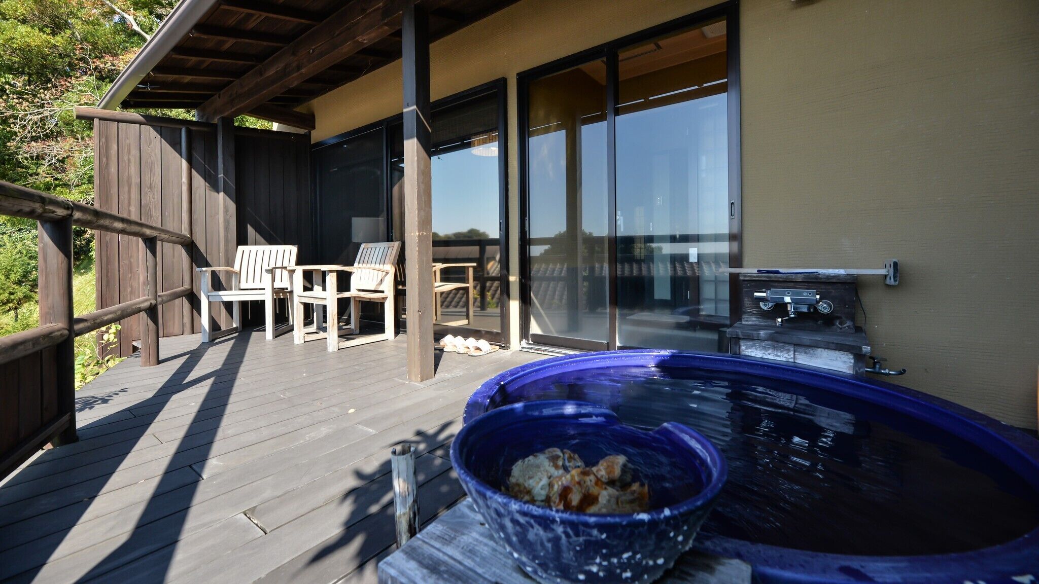 Een overdekt buitengebied met een jacuzzi, een barbecue en twee stoelen.