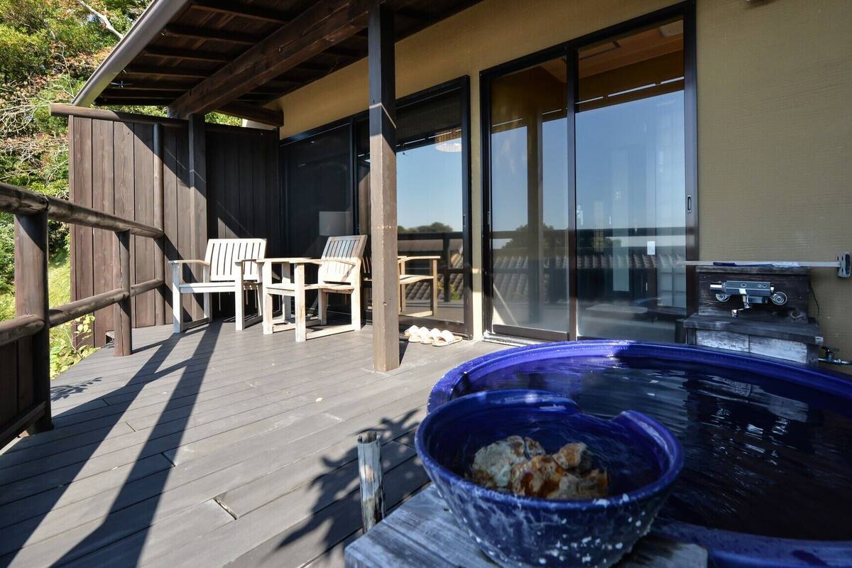 Un espace extérieur abrité comprenant un jacuzzi, un barbecue et deux chaises.