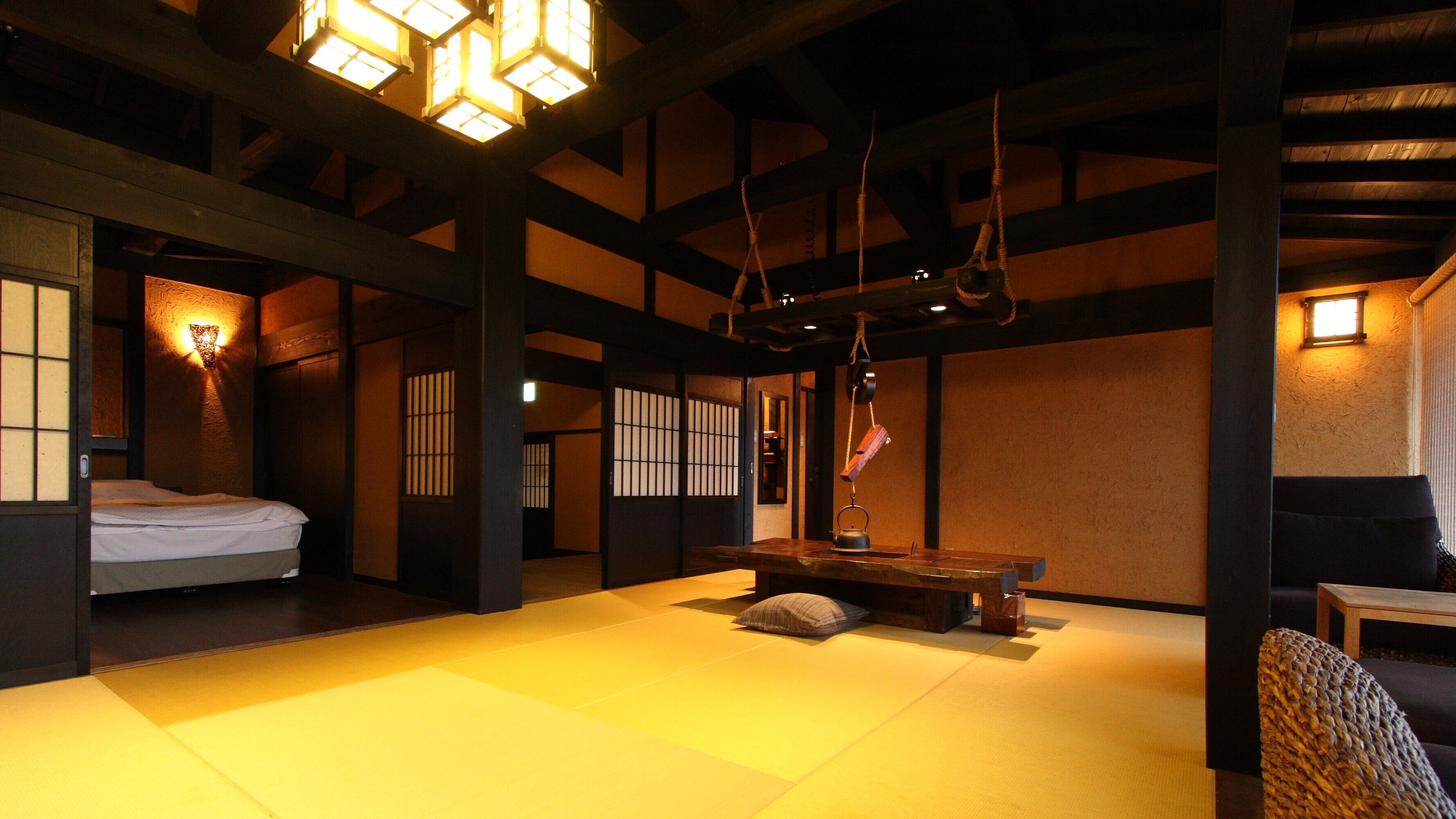 Een traditionele kamer met tatami matten, een bed, een tafel en een hangende touw.