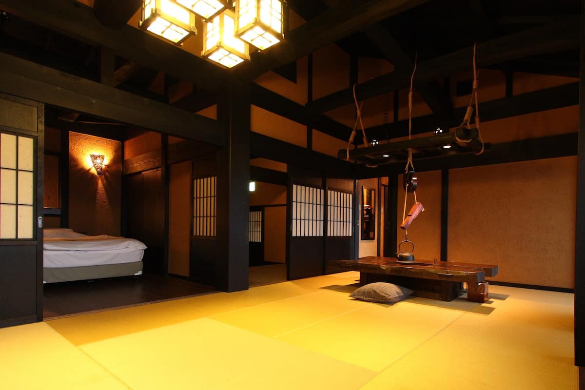 Una habitación tradicional con tatami, una cama, una mesa y una cuerda colgante.