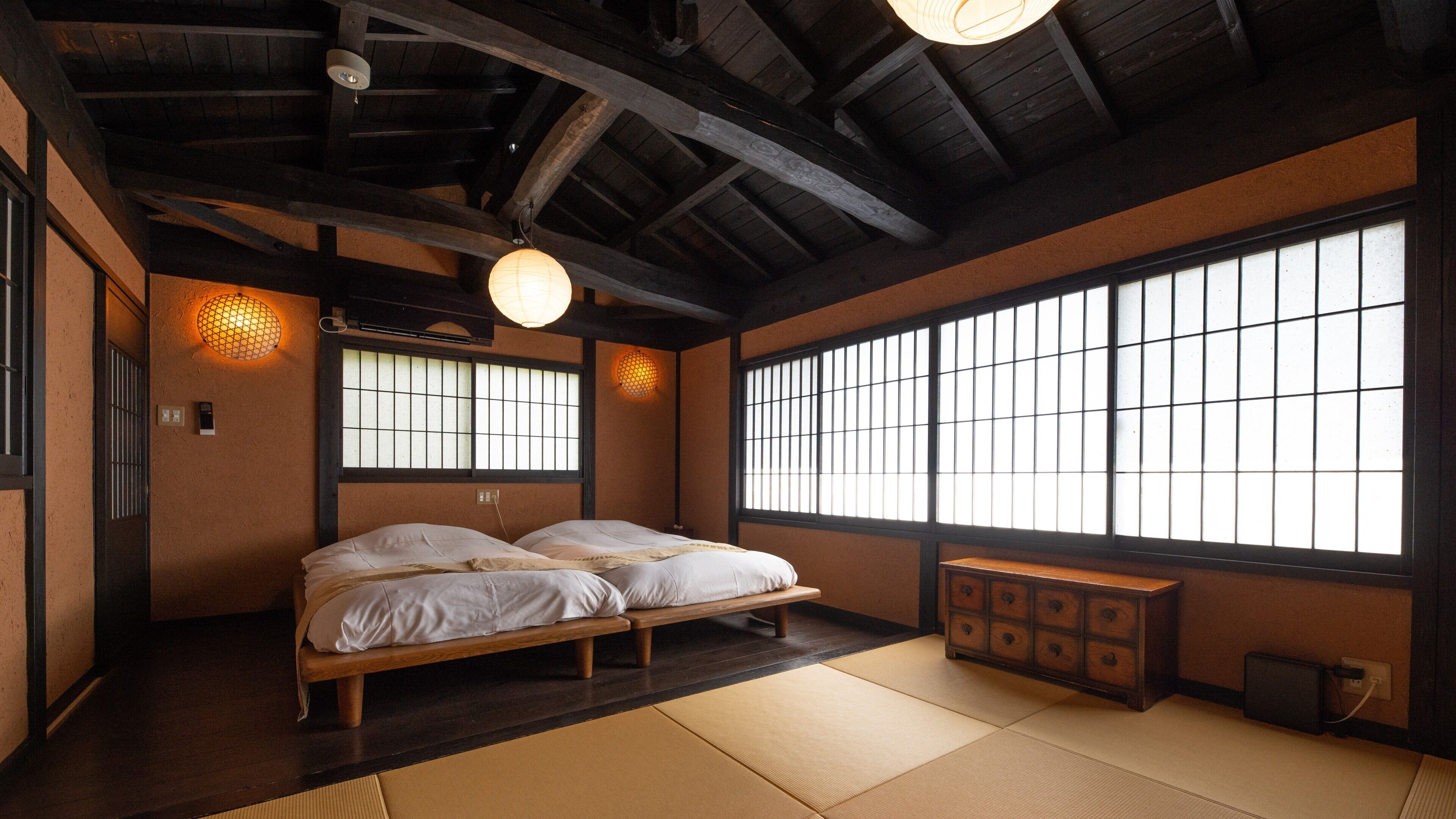 Een traditionele Japanse kamer met tatami vloeren, een houten bed, een kledingkast en grote ramen met een rasterpatroon.