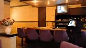 A room with a wooden table, purple chairs, a sofa, and a television.