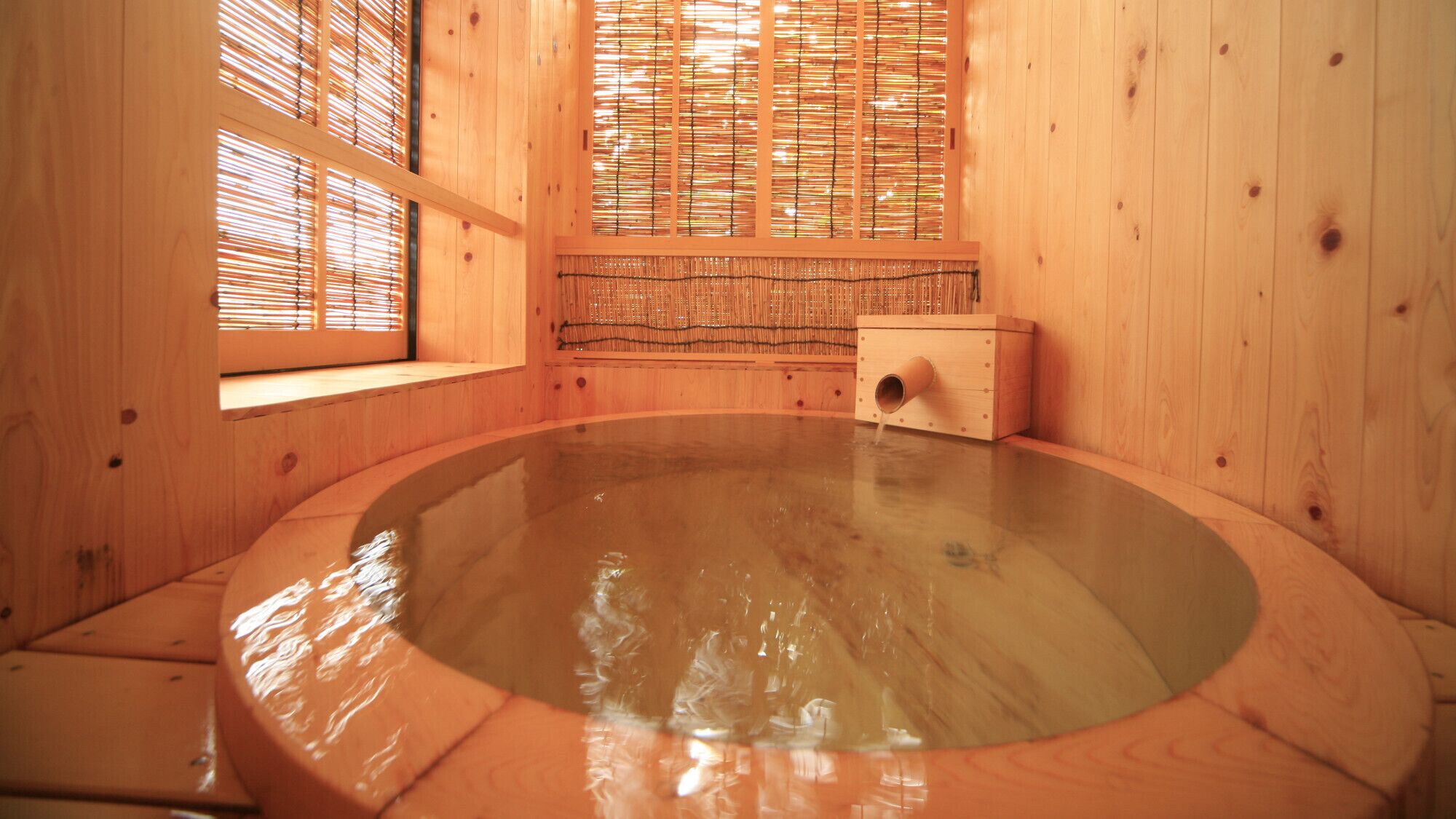 Uma banheira de hidromassagem de madeira com interior em madeira, uma janela com persianas de bambu e uma caixa de madeira.