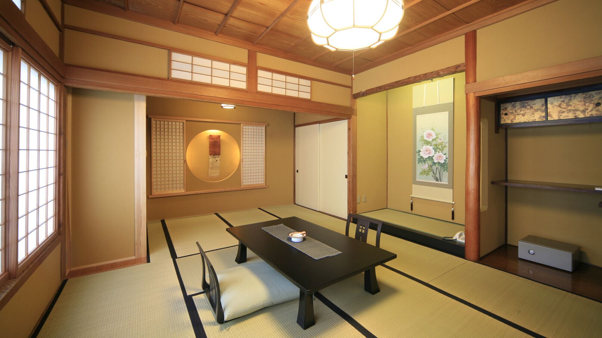 Um quarto japonês tradicional com tatames, uma mesa baixa, um pergaminho pendurado e uma porta deslizante.
