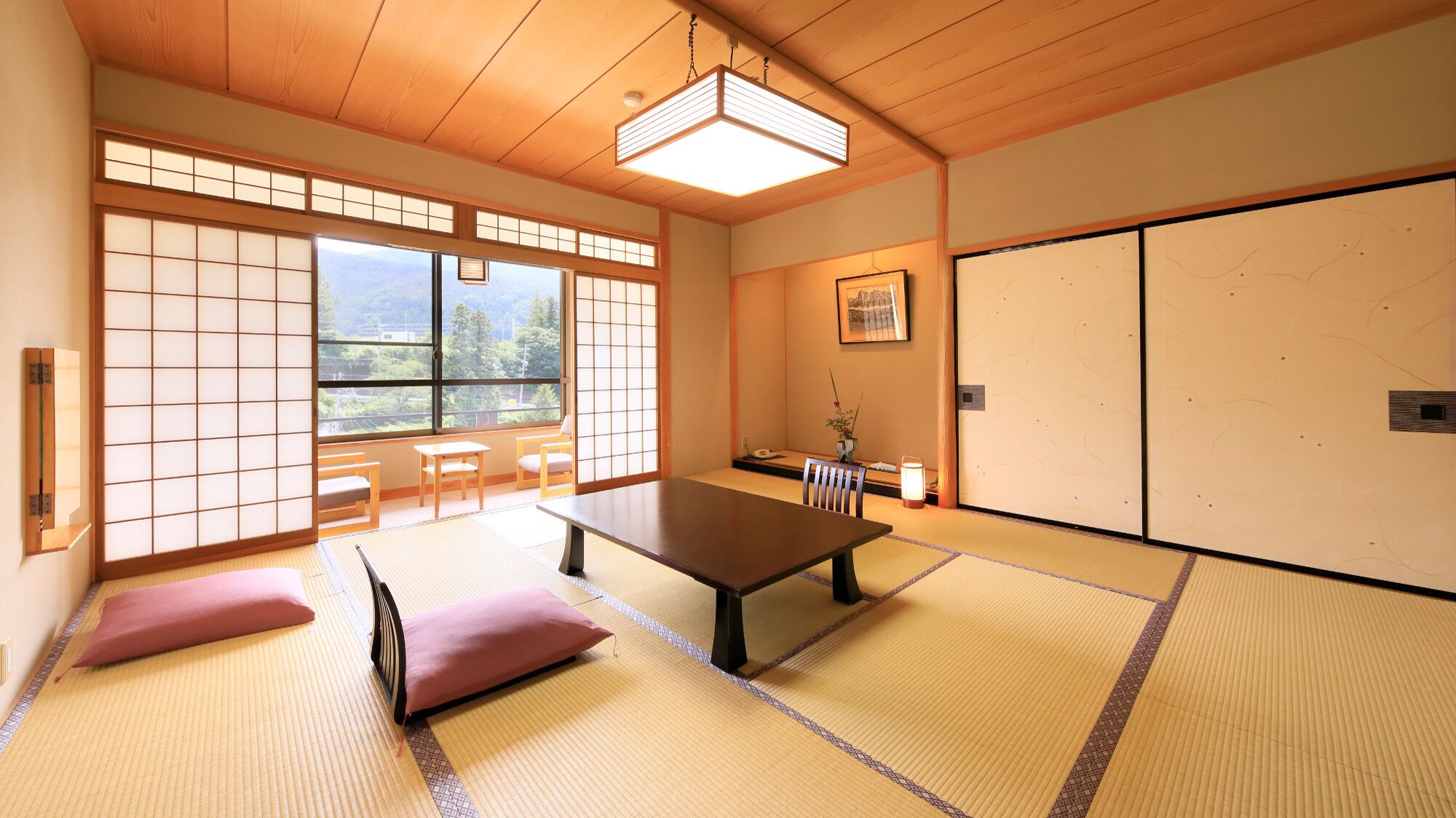 Um quarto japonês tradicional com tatames, uma mesa baixa, almofadas, portas deslizantes e vista para o verde.