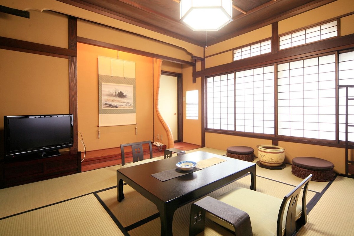 A traditional Japanese room with tatami flooring, a low table, and a television.