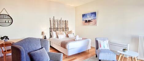A modern bedroom with a bed, a sofa, a small table, and a radiator.