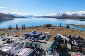 Un hôtel situé au bord d’un lac, doté d’un parking, de plusieurs bâtiments et offrant une vue sur des montagnes enneigées.