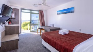 Une chambre d’hôtel avec un lit, un bureau avec une télévision, une chaise et un balcon avec vue.