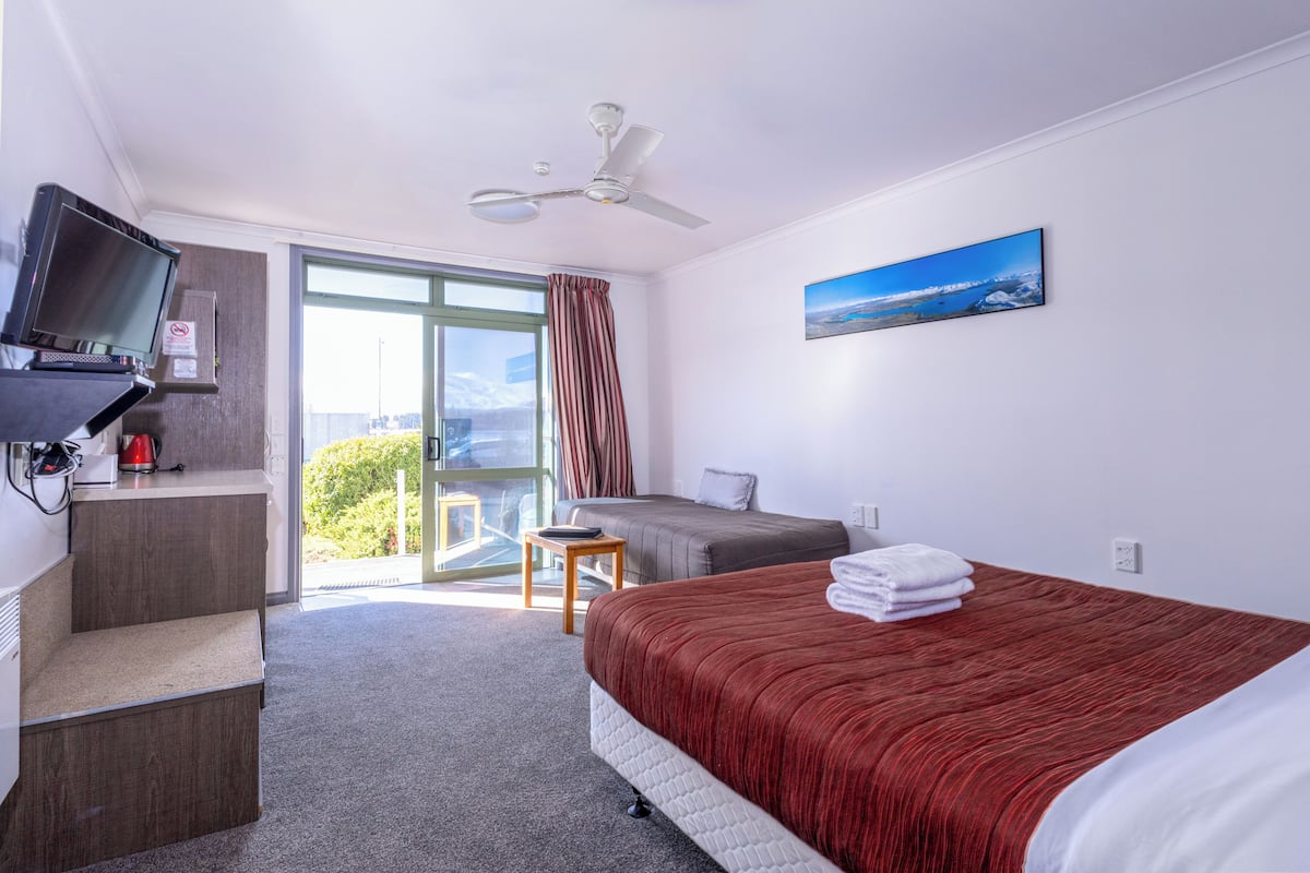 Een hotelkamer met een bed, een bureau met een televisie, een stoel en een balkon met uitzicht.