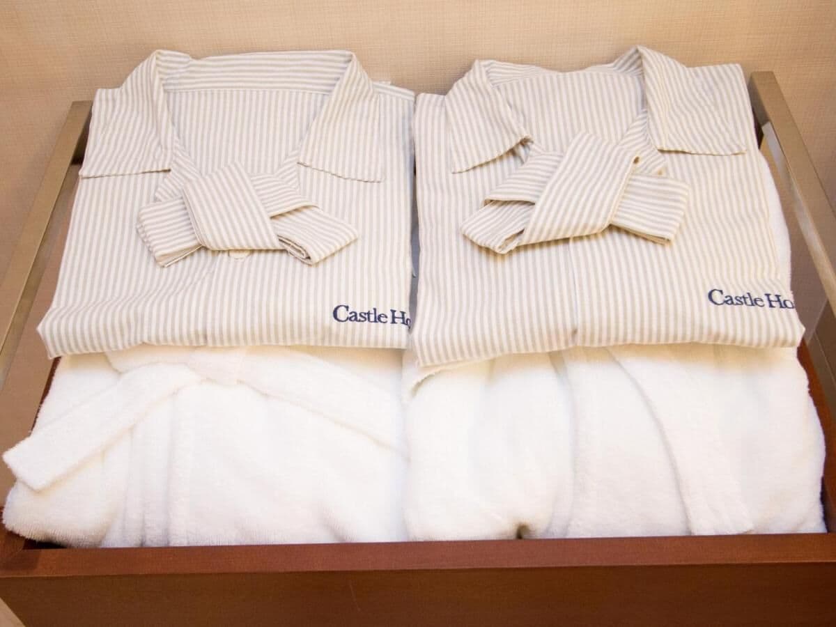 A box containing two sets of white striped pajamas with the brand name 'Castle Home' visible on the cuffs.