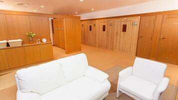 Un vestíbulo de hotel con taquillas de madera, un sofá blanco y un sillón blanco.