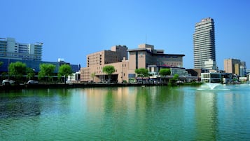 Waterfront hotel with a modern design, situated adjacent to a body of water and featuring a fountain.