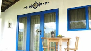 A room with a wooden table and chairs, a blue-framed window, and a door with glass panels. - Spicy Oasis (Curramore)