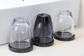 Trois objets transparents reposant sur une surface blanche, chacun ayant une base noire.