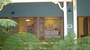A building with a green exterior and a covered outdoor area with ferns. - The Spotted Chook (Montville)
