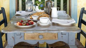A rustic dining table with a vintage design, surrounded by wicker chairs.