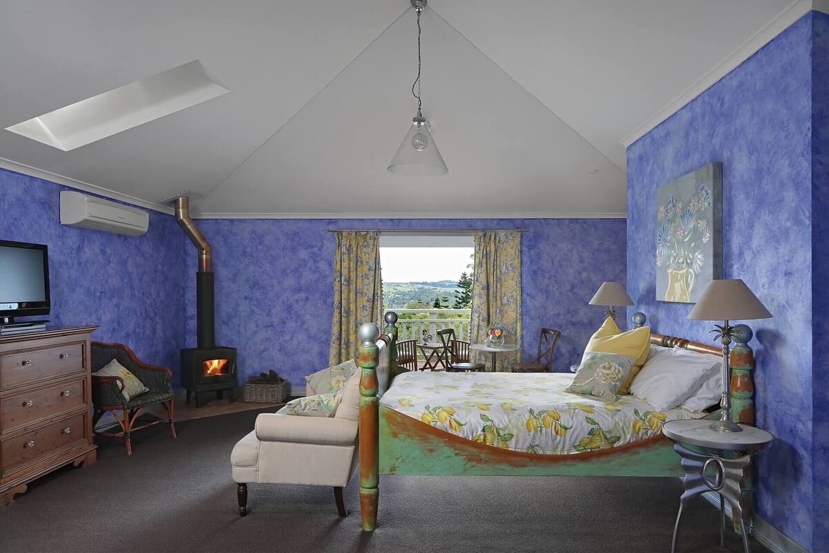 Un dormitorio con cama, televisor, chimenea y vista al exterior.