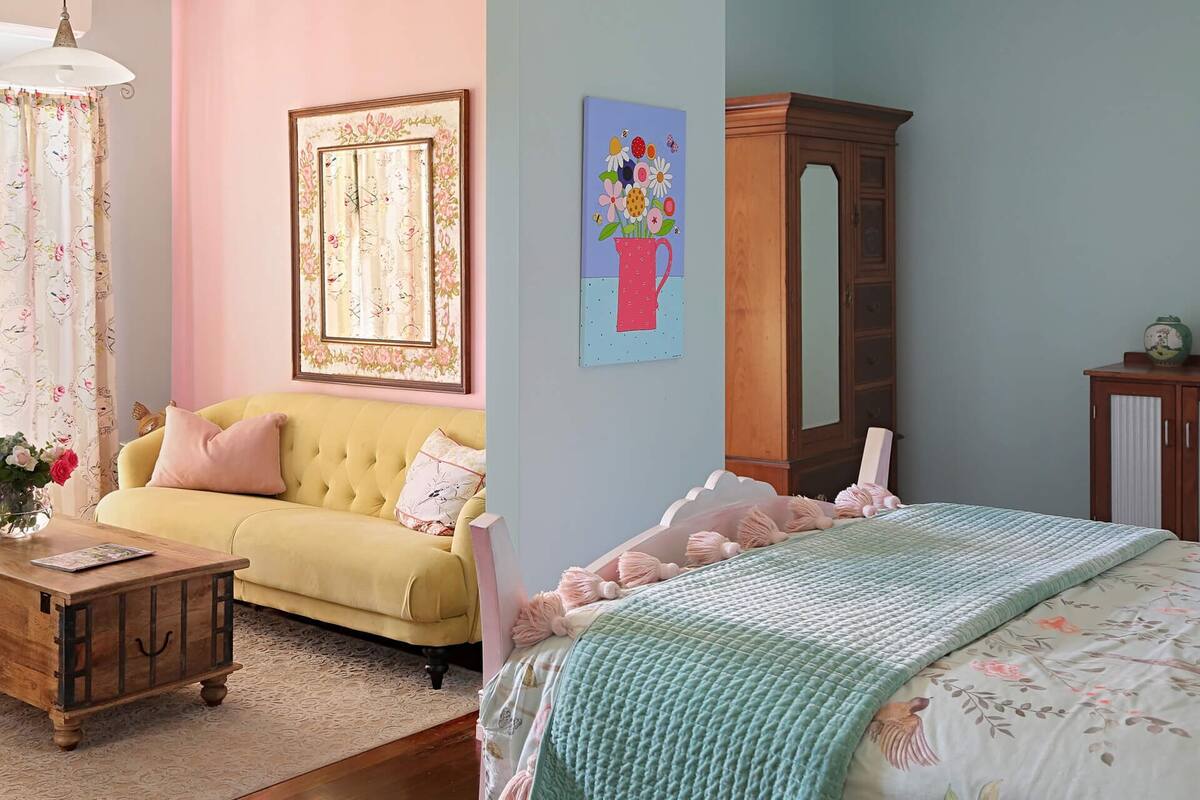 Una habitación con un sofá amarillo, un armario de madera y una cama con una manta verde.