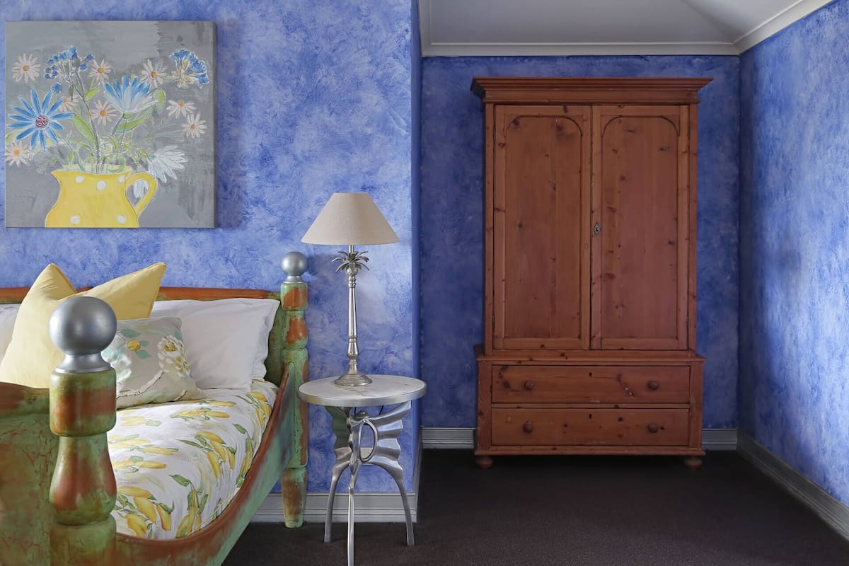 Un dormitorio con cama, mesita de noche, lámpara y armario.