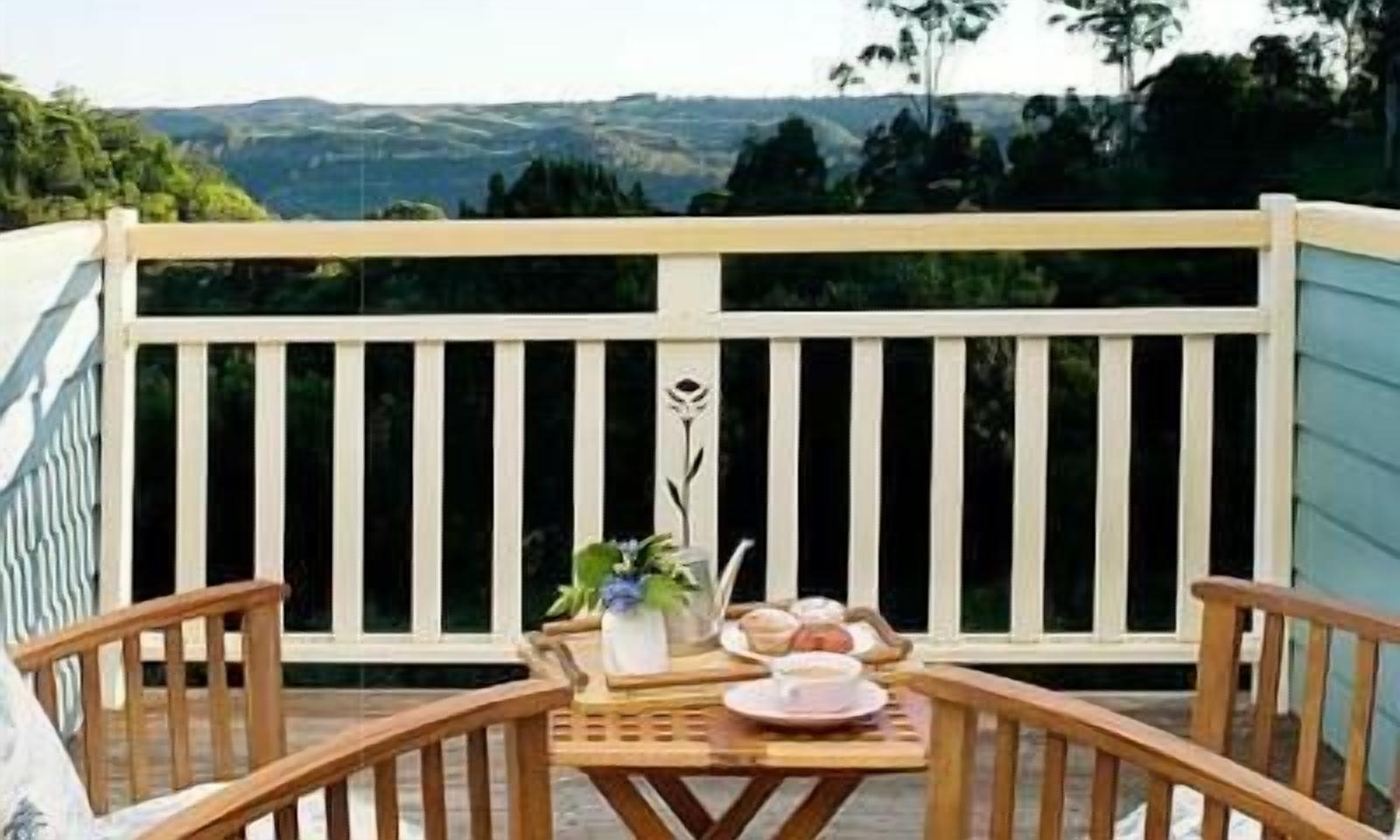 A wooden deck with a table set for two, overlooking a scenic landscape.