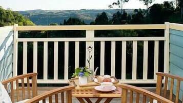 A wooden deck with a table set for two, overlooking a scenic landscape.