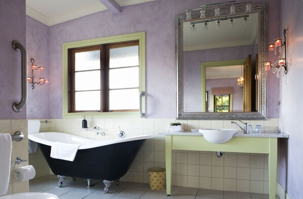 A bathroom with a freestanding bathtub, a vanity with a sink, and a large mirror.