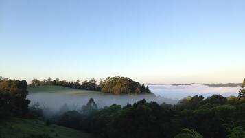 A landscape with a lake, forested hills, and a misty horizon.